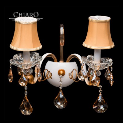 Светильник настенный бра Chiaro 282021502 Сицилия Светильник настенный бра Chiaro 282021502 СицилияКлассика<br>Описание модели 282021502: Элегантный образ светильника Сицилия запоминается своим фантастическим свечением. Бра оформлено в духе венецианских традиций, популярных в эпоху барокко и рококо. Основание декорировано деталями из окрашенного металла цветов белого и медового золота. Его дополняют изысканные рожки из выдувного белого стекла с золотой патиной. Под абажурами на центральной оси красуются аккуратно «вылепленные» розетки из прозрачного хрусталя, а в центре всей композиции возвышается величавый хрустальный кристалл, в многочисленных гранях которого множится и преобразуется сияние роскошного света. Украшением бра служат симметрично расположенные абажуры из светлого атласа и крупные подвески из искристого хрусталя цвета топаза. Выдающийся облик светильника Сицилия составит превосходное мнение о Вашем вкусе<br><br>S освещ. до, м2: 4<br>Тип товара: Светильник настенный бра<br>Тип лампы: накаливания / энергосбережения / LED-светодиодная<br>Тип цоколя: E14<br>Количество ламп: 2<br>Ширина, мм: 450<br>MAX мощность ламп, Вт: 40<br>Длина, мм: 400<br>Высота, мм: 250<br>Цвет арматуры: белый с золотистой патиной