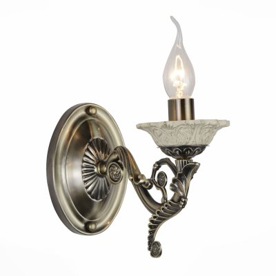 Светильник St Luce SL163.301.01 Светильник St Luce SL163.301.01Классические<br>Если Вы настроены купить светильник модели SL16330101, то обратите внимание: Сдержанность и одновременно торжественность характерны для светильников коллекции Vecchio. Глянцевое металлическое основание окрашено в цвет бронзы. Легкие ноты брутальности нивелируются изящными плафорами-свечками, декорированными керамическими чашами. Отсутствие каких-либо абажуров позволяет свету беспрепятственно распространяться по всему пространству комнаты равномерным потоком, освещая все вокруг. Светильники из коллекции Vecchio достойны королевских залов, но найдут место и в современном классическом интерьере зала, кабинета,холла гостиницы, ресторана.<br><br>Тип лампы: Накаливания / энергосбережения / светодиодная<br>Тип цоколя: E14<br>Количество ламп: 1<br>Ширина, мм: 105<br>MAX мощность ламп, Вт: 40<br>Высота, мм: 265